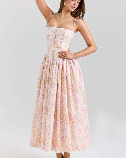Full-length view of a women's floral midi dress in peach and pink hues, featuring spaghetti straps and a cinched waist with a flowing skirt.