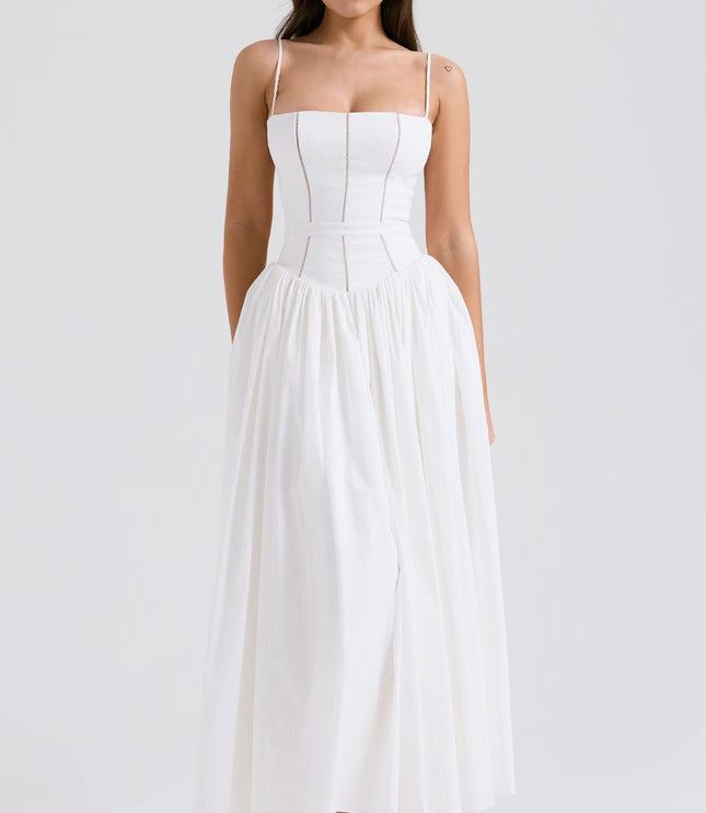 Front view of a women's white midi dress with spaghetti straps, a fitted bodice, and a full, pleated skirt, paired with green heels.