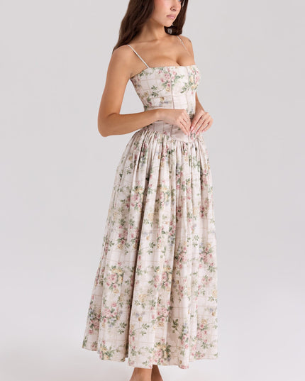 Three-quarter view of a women's floral midi dress with spaghetti straps, showcasing the delicate pink and green floral print on a cream background.