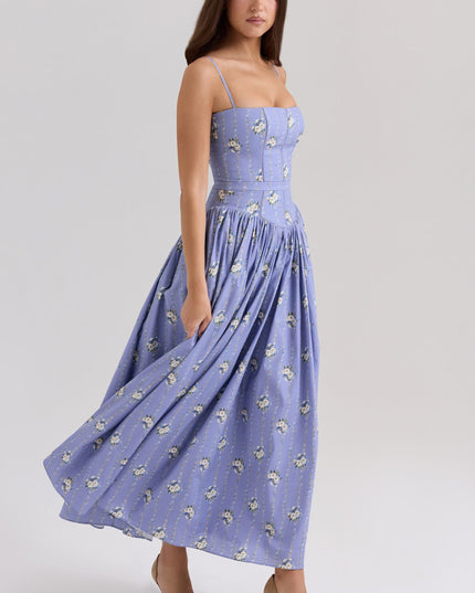 Women's summer floral midi dress in periwinkle blue with white floral patterns, featuring spaghetti straps and a flowing skirt in motion.