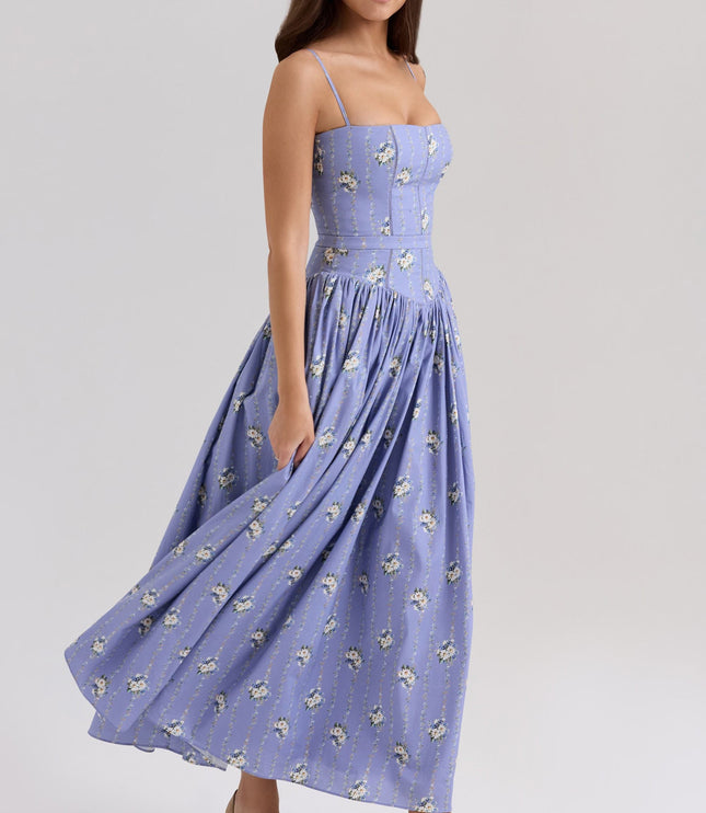 Women's summer floral midi dress in periwinkle blue with white floral patterns, featuring spaghetti straps and a flowing skirt in motion.