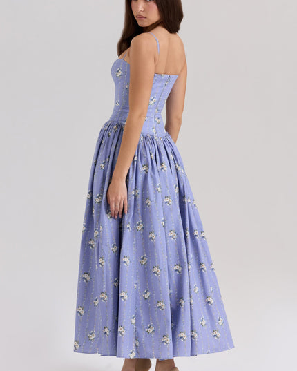 Back view of a women's periwinkle blue floral midi dress with spaghetti straps and a full skirt, paired with tan heels.