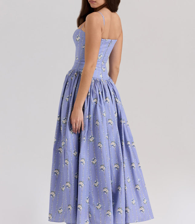 Back view of a women's periwinkle blue floral midi dress with spaghetti straps and a full skirt, paired with tan heels.