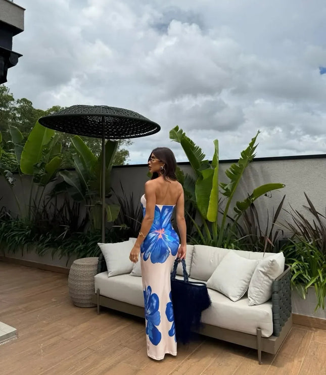 Front view of cream floral strapless maxi dress with orange flower print by a pool