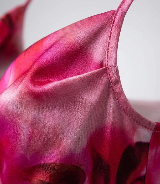 Close-up of pink floral satin fabric on a women's summer dress with thin strap