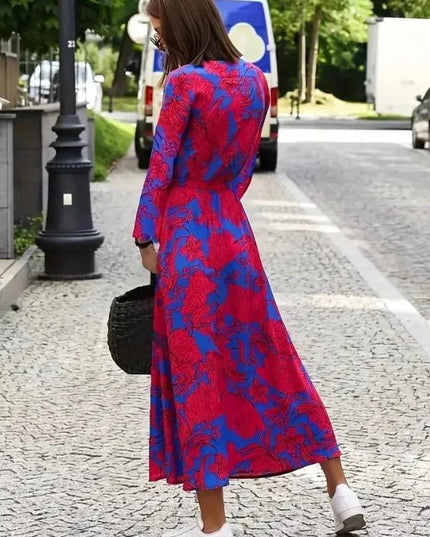 Back view of a women's floral midi dress in magenta and blue with long sleeves and flowing skirt
