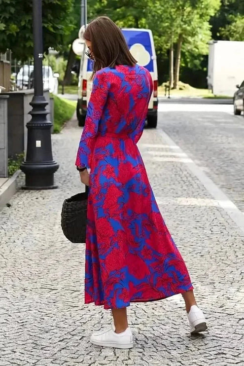 Back view of a women's floral midi dress in magenta and blue with long sleeves and flowing skirt