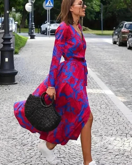 Profile view of a V neck floral midi dress in magenta and blue with wrap style skirt
