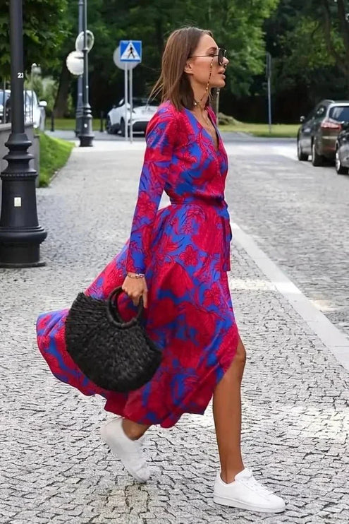 Profile view of a V neck floral midi dress in magenta and blue with wrap style skirt