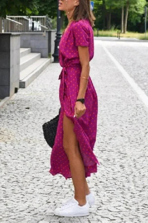 Side view of a magenta polka dot summer dress with V neck, tie waist and midi length hem