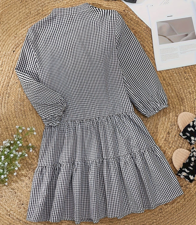 Black and white gingham mini dress laid flat, showing long sleeves and tiered hem