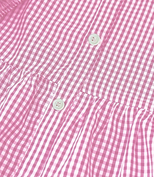 Close-up of pink gingham mini dress fabric with buttons and tiered seam detail