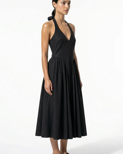 Side view of black halter midi dress showing fitted bodice and flowing skirt