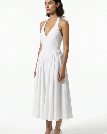 Side view of white halter midi dress with fitted waist and soft pleated skirt