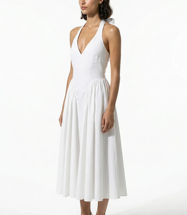 Side view of white halter midi dress with fitted waist and soft pleated skirt