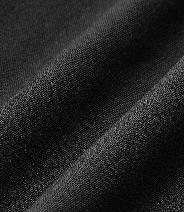 Close-up of black pleated maxi skirt fabric showing smooth textured weave and soft drape