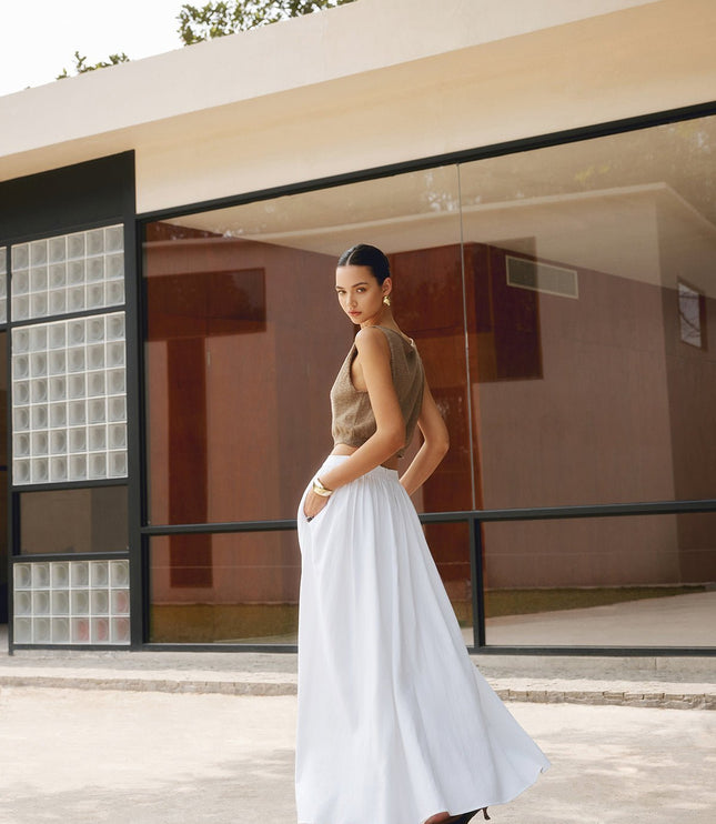Side view of white high waisted maxi skirt with pleats and ankle-length flow