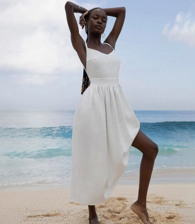 White linen maxi dress with one-shoulder tie strap and flowing skirt on the beach