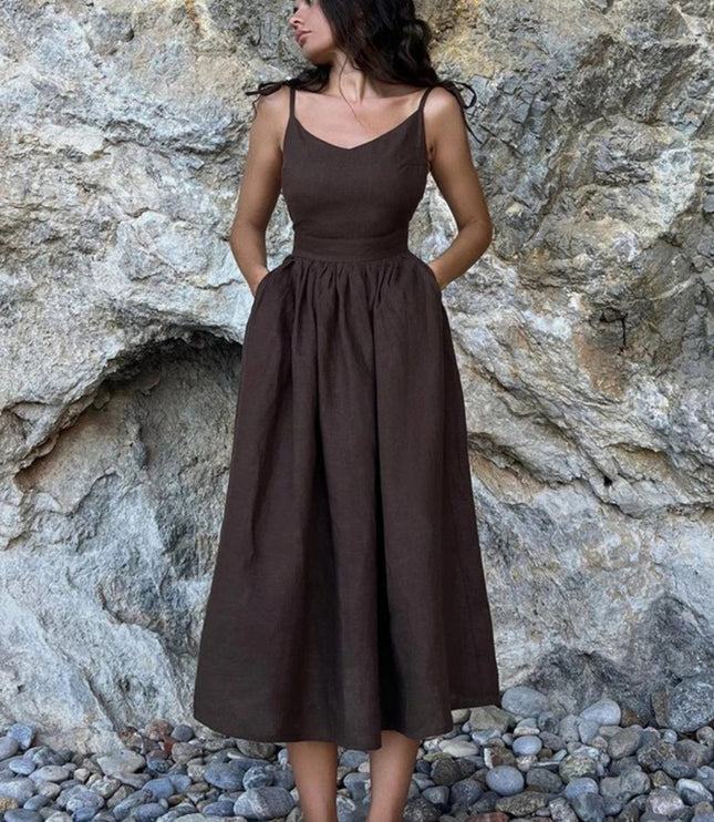 Dark brown linen maxi dress with spaghetti straps and full gathered skirt against rock wall