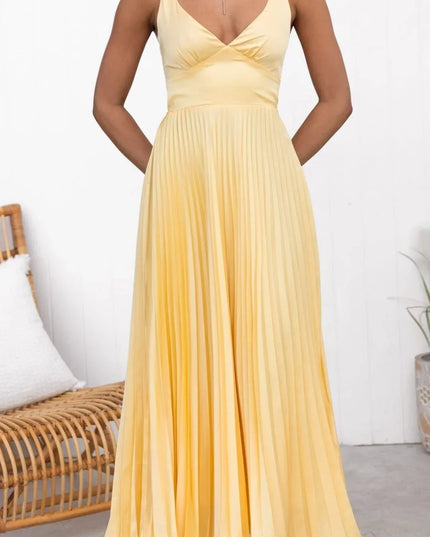 Front view of yellow summer maxi dress with pleated skirt and deep V neck, hands in pockets