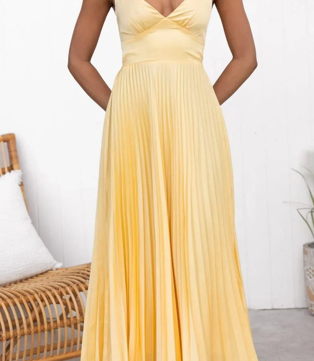 Front view of yellow summer maxi dress with pleated skirt and deep V neck, hands in pockets