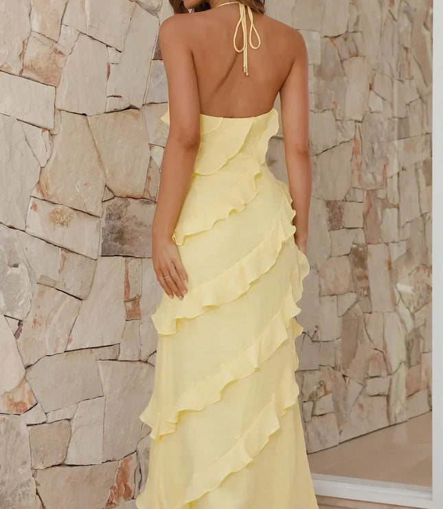 Back view of pale yellow maxi dress with open back and ruffle layers, styled with heeled sandals