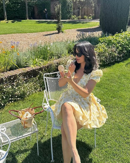 Garden scene featuring a yellow floral V neck mini dress with puff sleeves and flared skirt