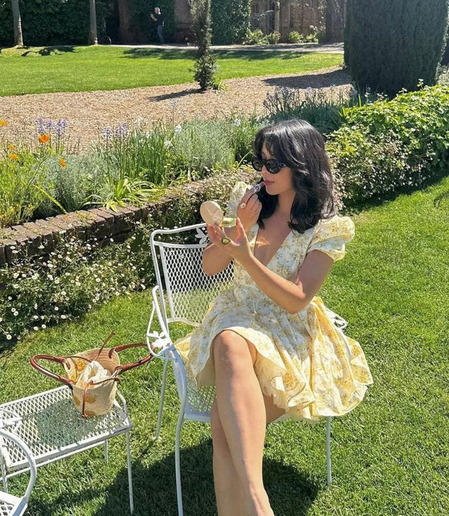 Garden scene featuring a yellow floral V neck mini dress with puff sleeves and flared skirt