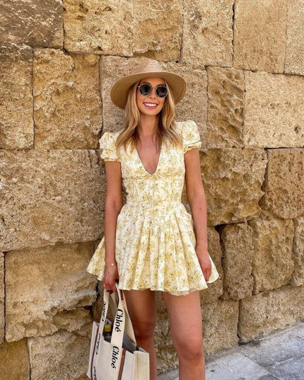 Front view of yellow floral mini dress with deep V neck, puff sleeves, and cinched waist