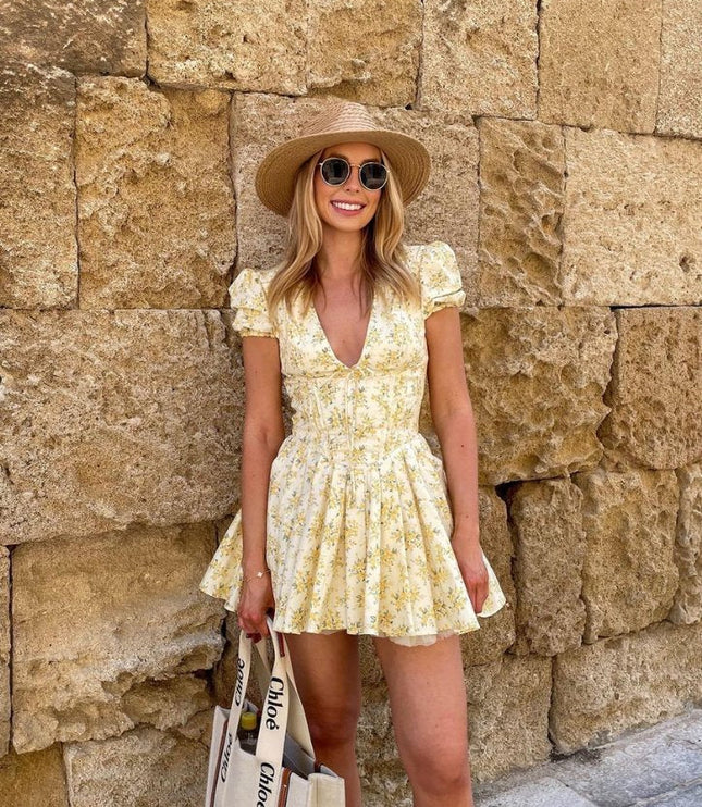 Front view of yellow floral mini dress with deep V neck, puff sleeves, and cinched waist