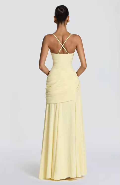 Back view of yellow formal maxi dress showing crossback straps and asymmetrical draping