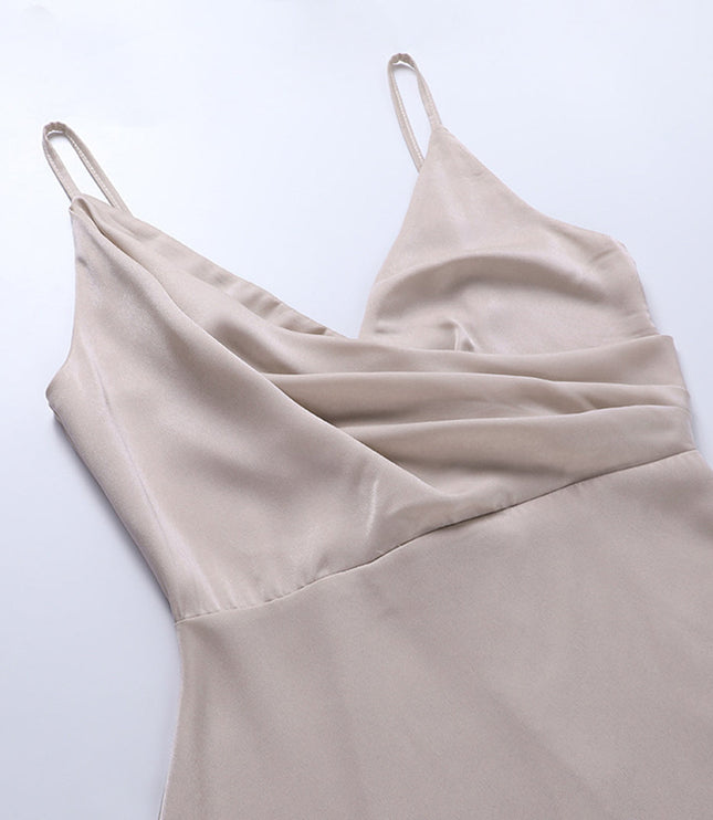 Top-down view of the draped V-neckline and delicate spaghetti straps of a beige women's maxi slip dress.