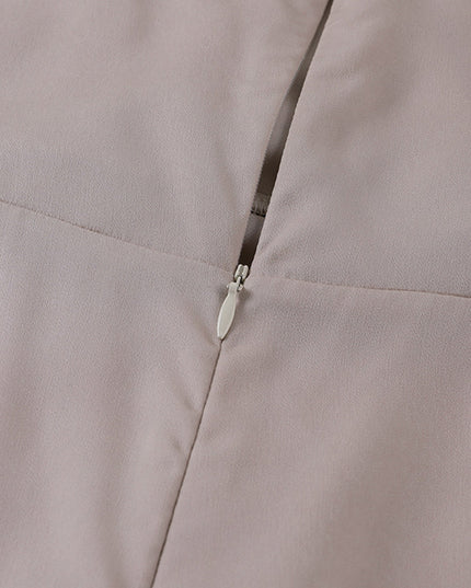 Close-up of the invisible zipper closure on the back of a beige women's V-neck maxi slip dress.