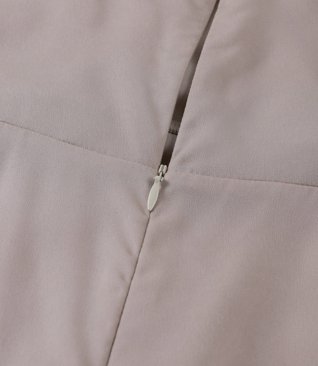 Close-up of the invisible zipper closure on the back of a beige women's V-neck maxi slip dress.
