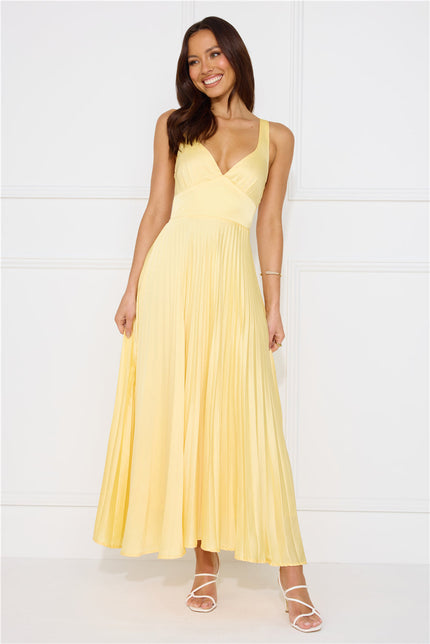 Front view of pale yellow sleeveless maxi dress with wrapped bodice and pleated skirt