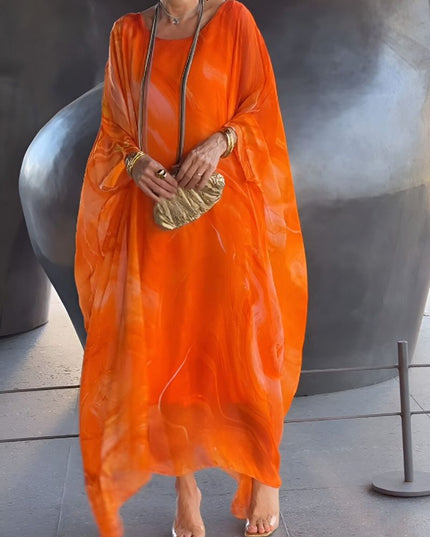 Front view of orange abstract print maxi dress with flowing sheer overlay