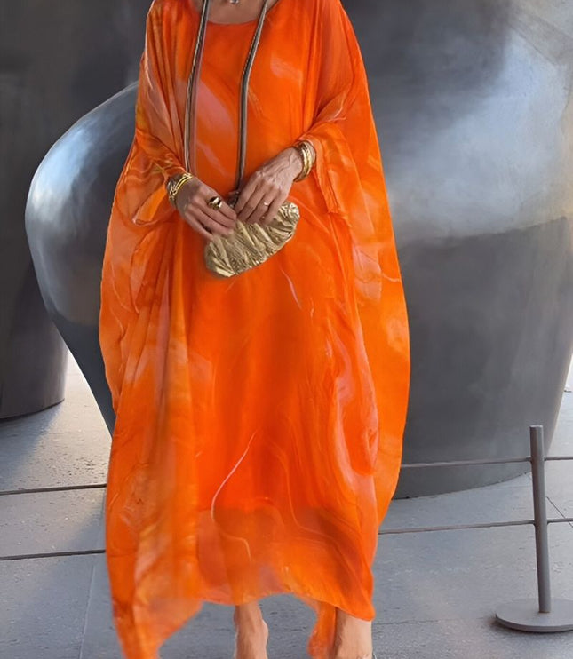 Front view of orange abstract print maxi dress with flowing sheer overlay