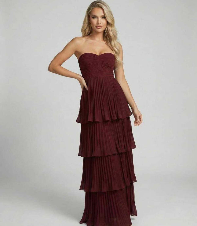 Front view of burgundy strapless wedding guest maxi dress with layered pleated skirt