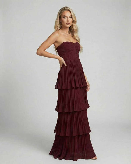 Side view of burgundy strapless maxi dress with pleated layers and flowy skirt