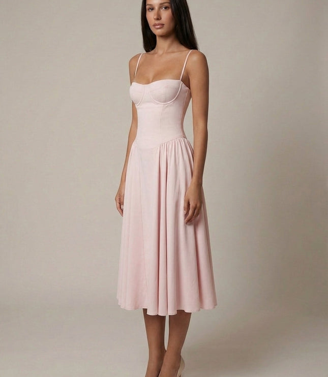 Side view of light pink midi dress with fitted corset top and flowing wedding guest skirt