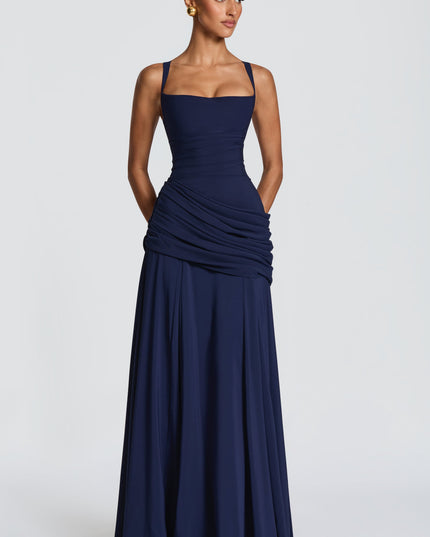 Navy wedding guest maxi dress angled view showing fitted bodice and draped ruched wrap skirt