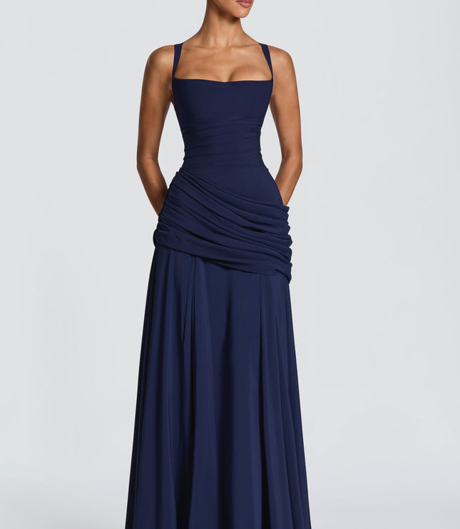 Navy wedding guest maxi dress angled view showing fitted bodice and draped ruched wrap skirt