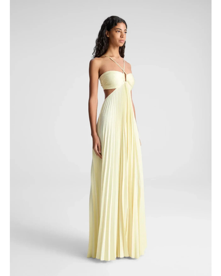 Side view of pale yellow wedding guest halter maxi pleated dress with flowing skirt and cutout waist