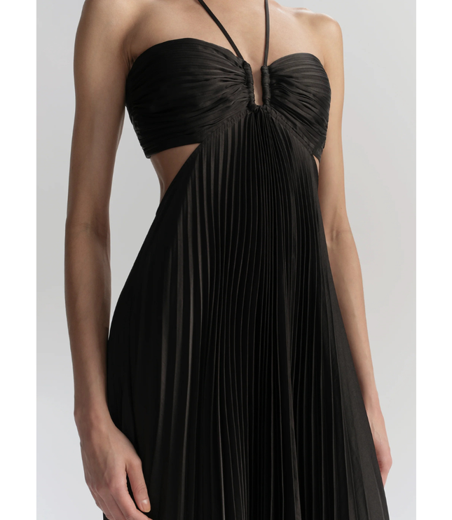 Close-up of black halter maxi pleated dress showing ruched bodice, waist cutouts, and pleats