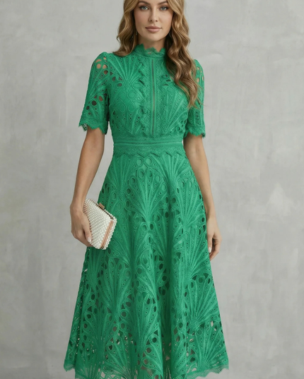 Green lace midi dress with high neck, short sleeves, and scalloped hem, styled with a pearl clutch