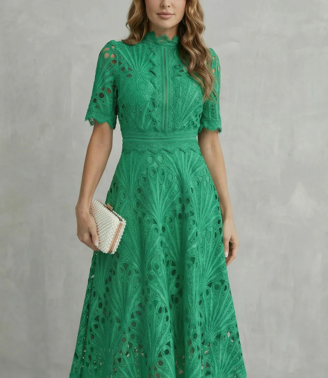 Green lace midi dress with high neck, short sleeves, and scalloped hem, styled with a pearl clutch