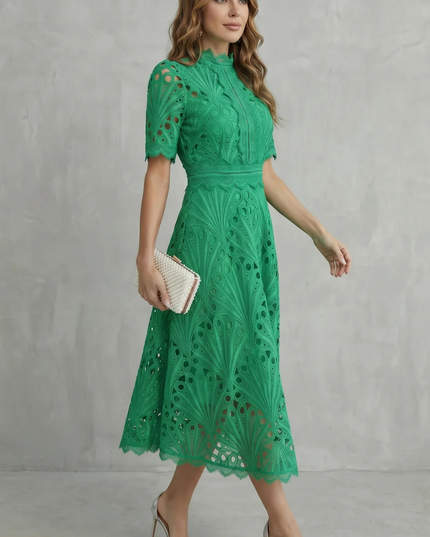 Side view of green wedding guest lace midi dress with high neck and fitted waist, worn with silver heels