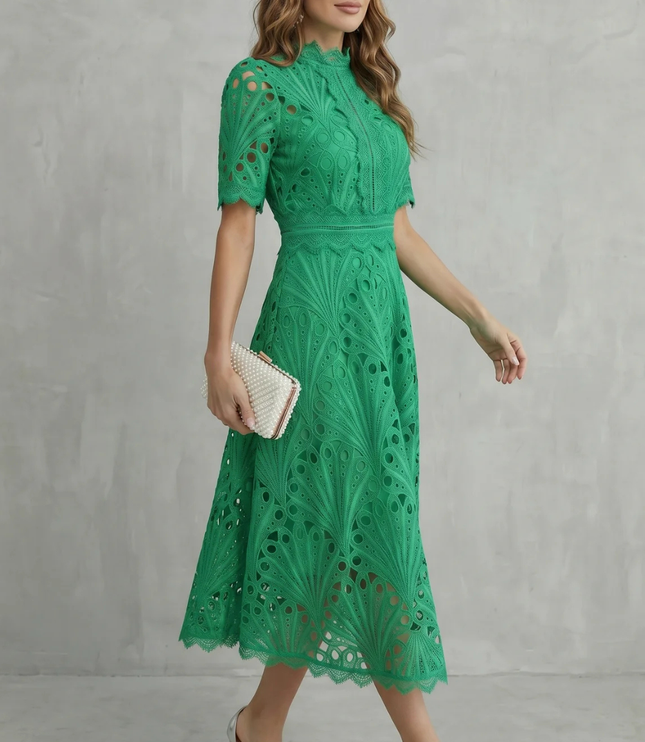 Side view of green wedding guest lace midi dress with high neck and fitted waist, worn with silver heels