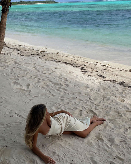 Woman reclining in a strapless white maxi dress with lace trim and soft draped bodice