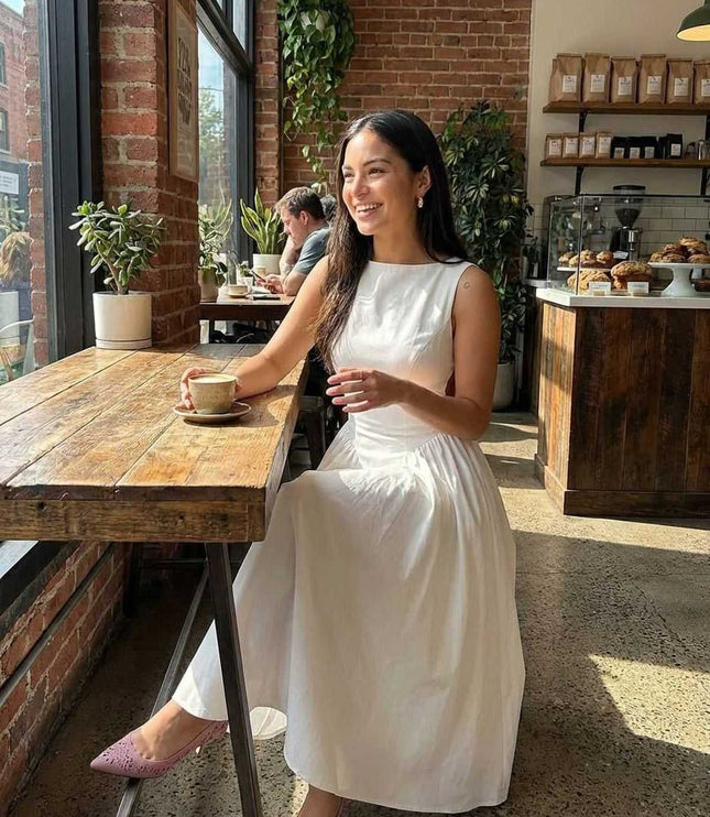 White side cutout midi dress styled in a cafe, showing the sleeveless fit and full skirt